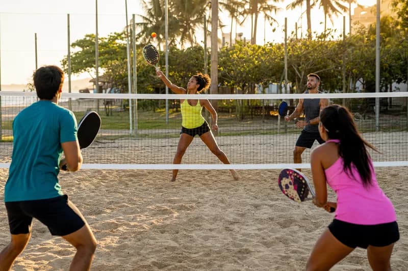 Partida de beach tennis na areia com jogadores dos dois lados da rede